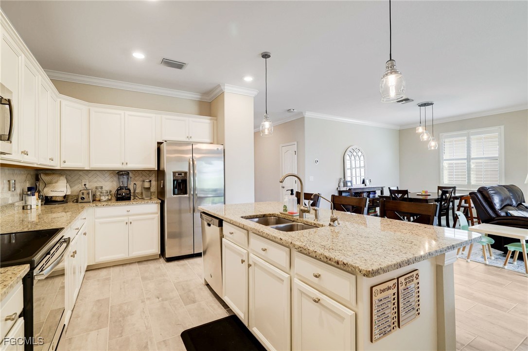 9778 Mirada Boulevard Fort Myers, FL 33908 - Photo 10 of 29 a kitchen with a sink a stove a refrigerator and white cabinets