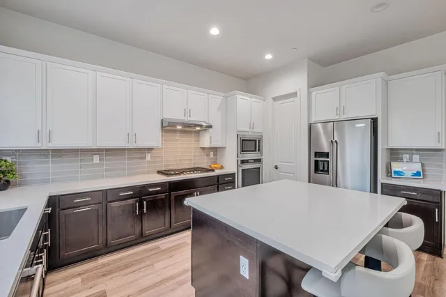 a kitchen with stainless steel appliances a stove a sink a refrigerator and cabinets