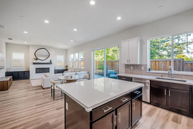 a kitchen with a stove a sink dishwasher a dining table and chairs with wooden floor