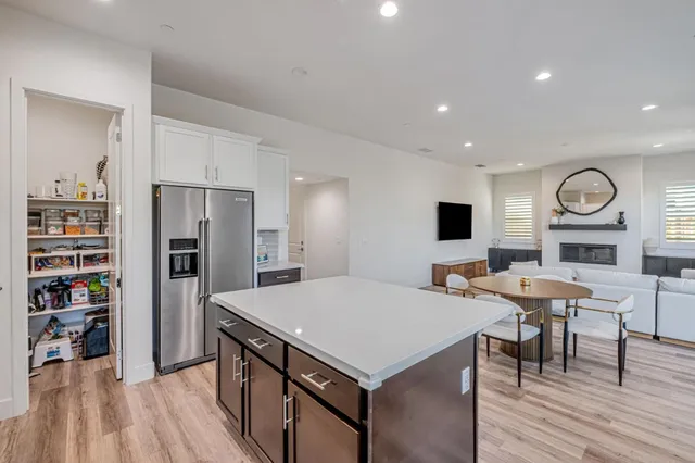 a living room with stainless steel appliances furniture a fireplace and a open kitchen view