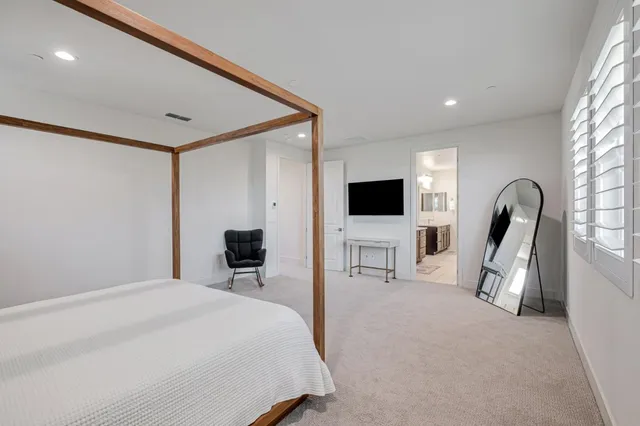 a bedroom with a bed and a flat tv screen on wall