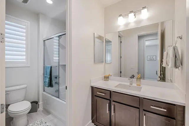 a bathroom with a sink a toilet a mirror and shower