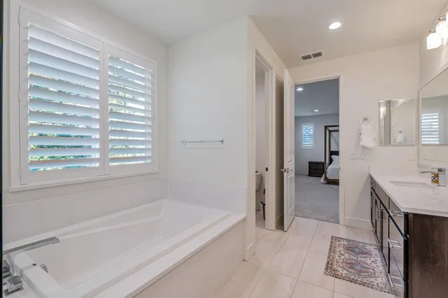 a spacious bathroom with a tub sink and mirror