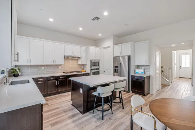 a kitchen with refrigerator a stove a sink dishwasher with a dining table and chairs