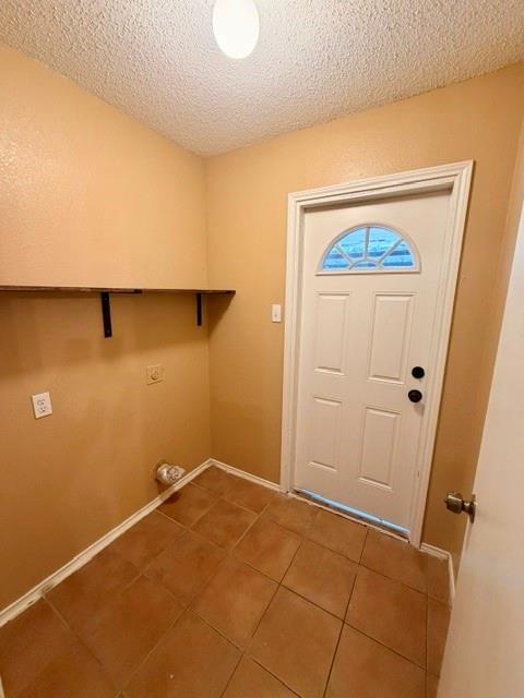 2604 Crix Lane Fort Worth, TX 76140 - Photo 4 of 13 Utility area featuring a white paneled door with an arched window, tile flooring, and a wall-mounted wood-finish shelf