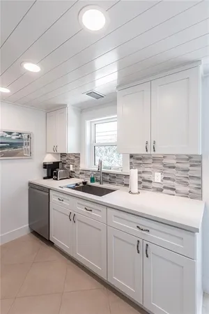 a kitchen with granite countertop white cabinets white stainless steel appliances with a sink and dishwasher