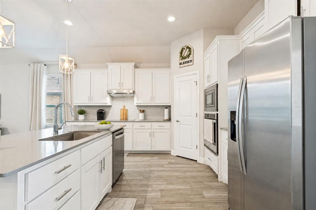 617 Mesquite Grove Road Midlothian, TX 76065 - Photo 8 of 25 Gourmet kitchen with white cabinetry, stainless steel appliances, a center island with sink, quartz countertops, and wood-finish flooring