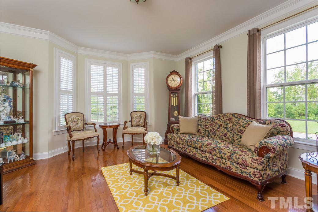 404 Powers Ferry Road Cary, NC 27519 - Photo 2 of 25 Formal living room showcases gleaming hardwood floors, large windows and bay with beautiful plantation shutters, detailed base molding and extra wide crown moldings.
