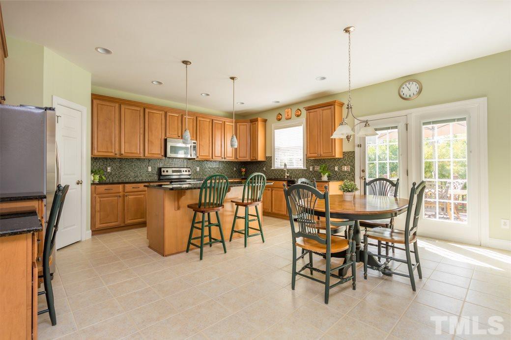 404 Powers Ferry Road Cary, NC 27519 - Photo 6 of 25 Kitchen features ample counter space and island for extra dining area. Work space with matching granite counter is perfect for the busy homeowners.