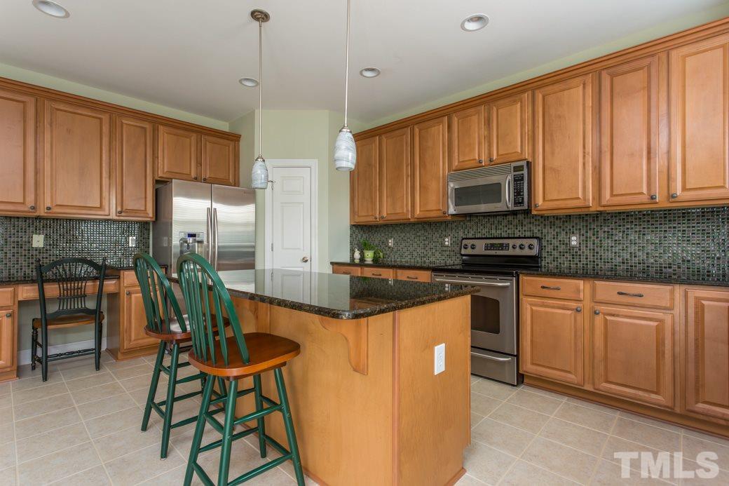 404 Powers Ferry Road Cary, NC 27519 - Photo 8 of 25 Granite countertops highlighted with mosaic tile backsplash, stainless steel appliances, upgraded maple cabinetry with iron handles, extra-large granite island with pendant lighting, and spacious pantry complete this cook’s dream kitchen.