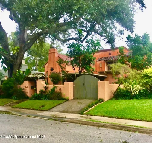 a front view of house with a garden and trees