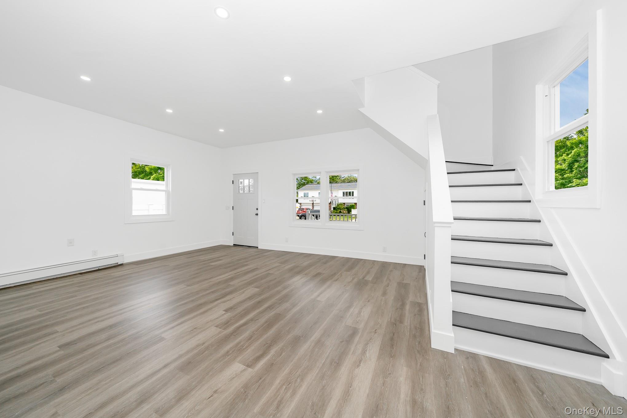 24 Calvert Avenue West Babylon, NY 11704 - Photo 12 of 28 Unfurnished living room featuring recessed lighting, light wood-type flooring, stairway, and a baseboard radiator