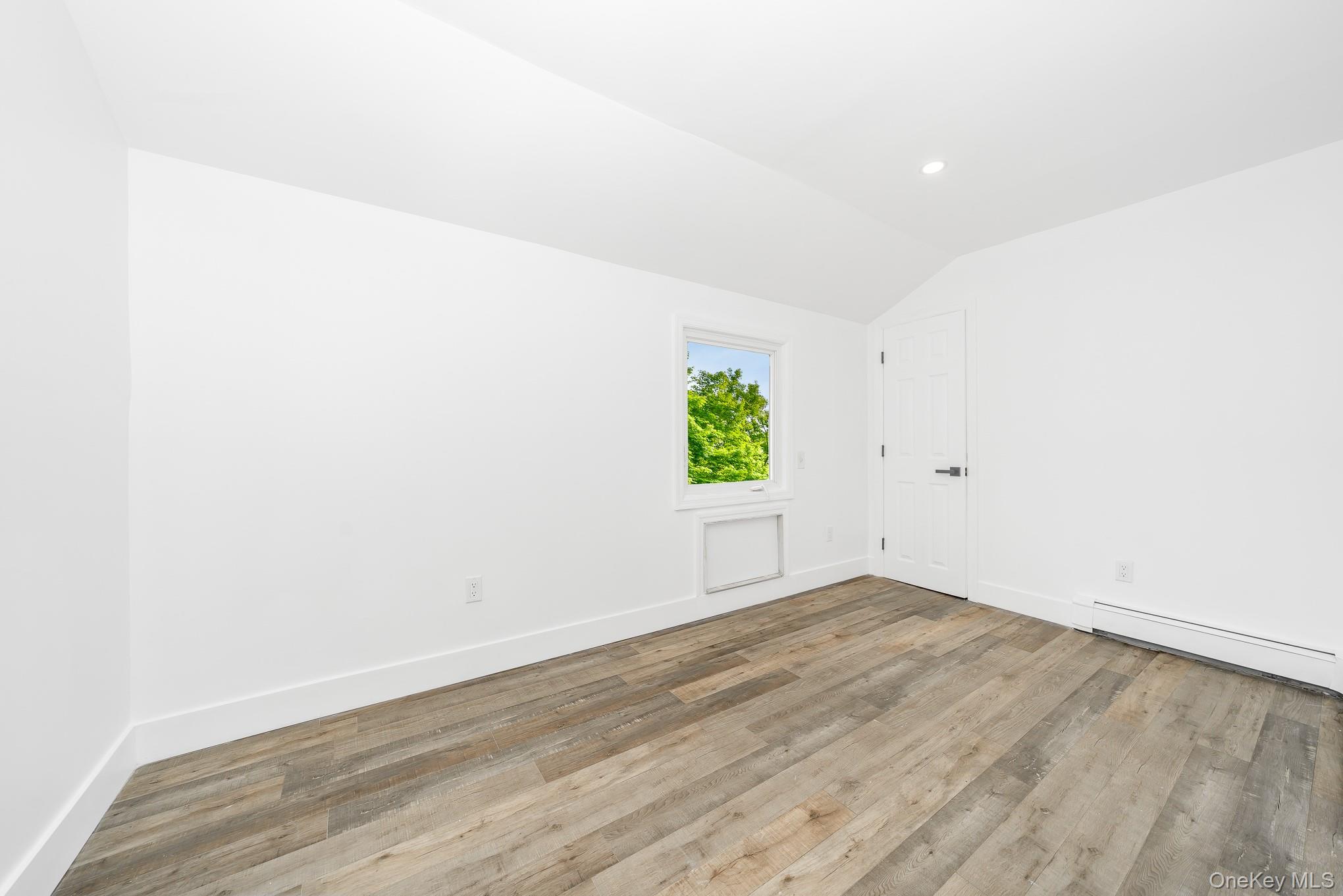 24 Calvert Avenue West Babylon, NY 11704 - Photo 16 of 28 Spare room featuring wood finished floors, lofted ceiling, a baseboard heating unit, and recessed lighting