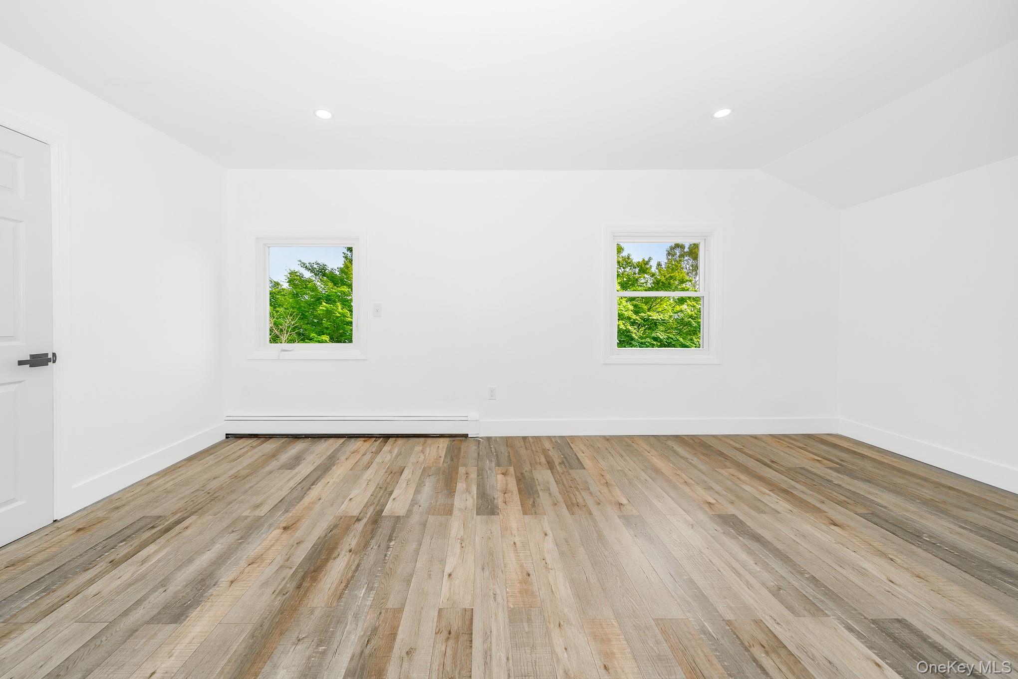 24 Calvert Avenue West Babylon, NY 11704 - Photo 18 of 28 Empty room featuring light wood-type flooring, recessed lighting, a baseboard radiator, and lofted ceiling