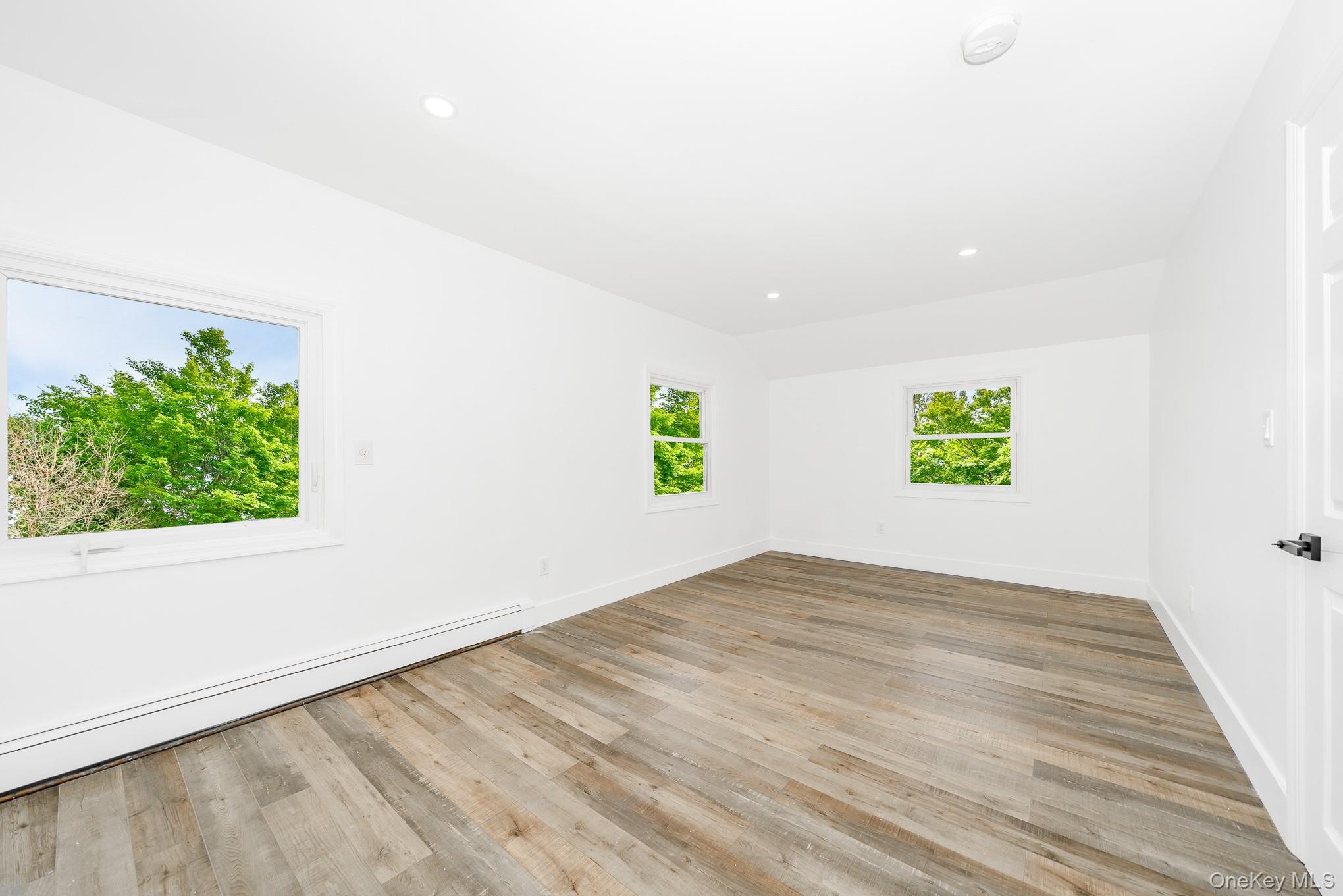 24 Calvert Avenue West Babylon, NY 11704 - Photo 19 of 28 Empty room featuring recessed lighting, a baseboard radiator, light wood-type flooring, and lofted ceiling