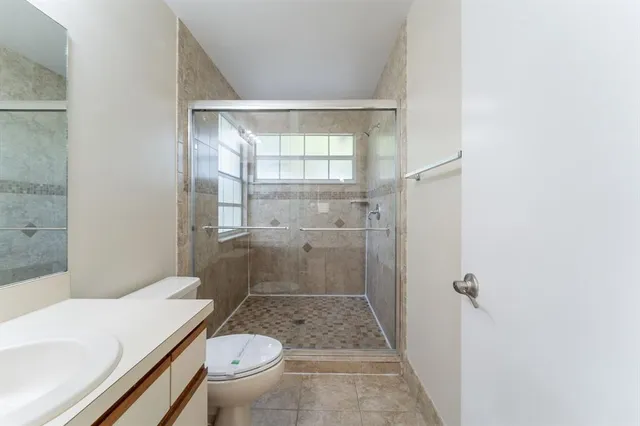 a bathroom with a granite countertop toilet a sink and a mirror