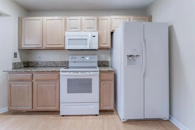 a kitchen with white cabinets and white appliances