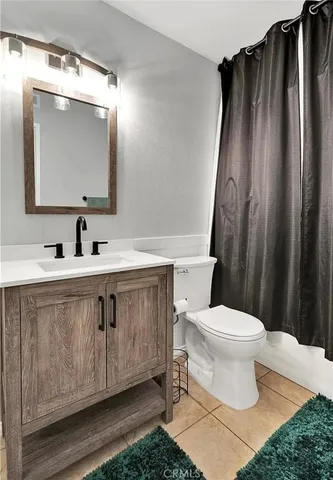 a bathroom with a sink a toilet a mirror and shower curtain