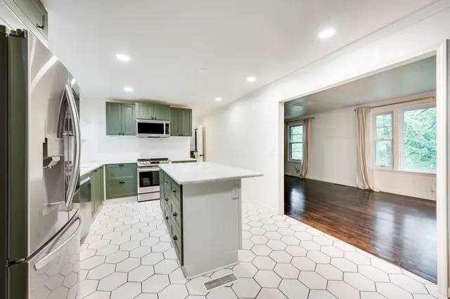 a kitchen with stainless steel appliances kitchen island granite countertop a refrigerator and a stove top oven