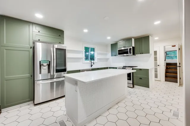 a large kitchen with stainless steel appliances a sink and a refrigerator