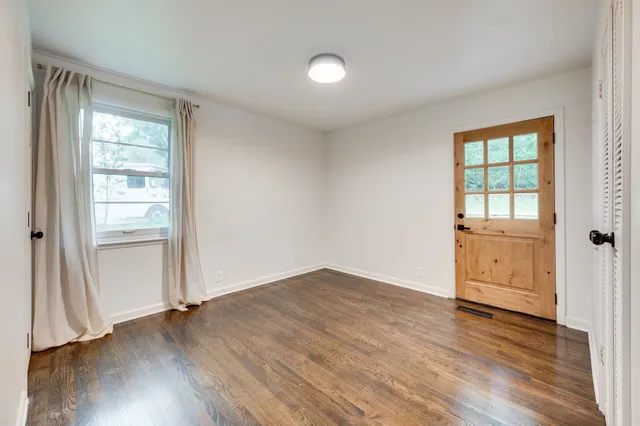 an empty room with wooden floor cabinet and windows