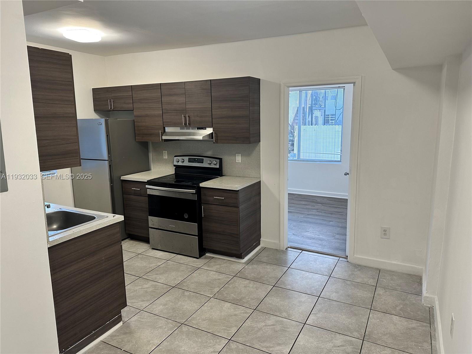 1129 Northwest 3rd Street, Unit 202 Miami, FL 33128 - Photo 2 of 10 a kitchen with stainless steel appliances kitchen island granite countertop a sink and a stove