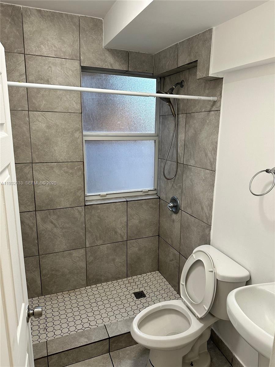 1129 Northwest 3rd Street, Unit 202 Miami, FL 33128 - Photo 5 of 10 a bathroom with a toilet a sink and shower