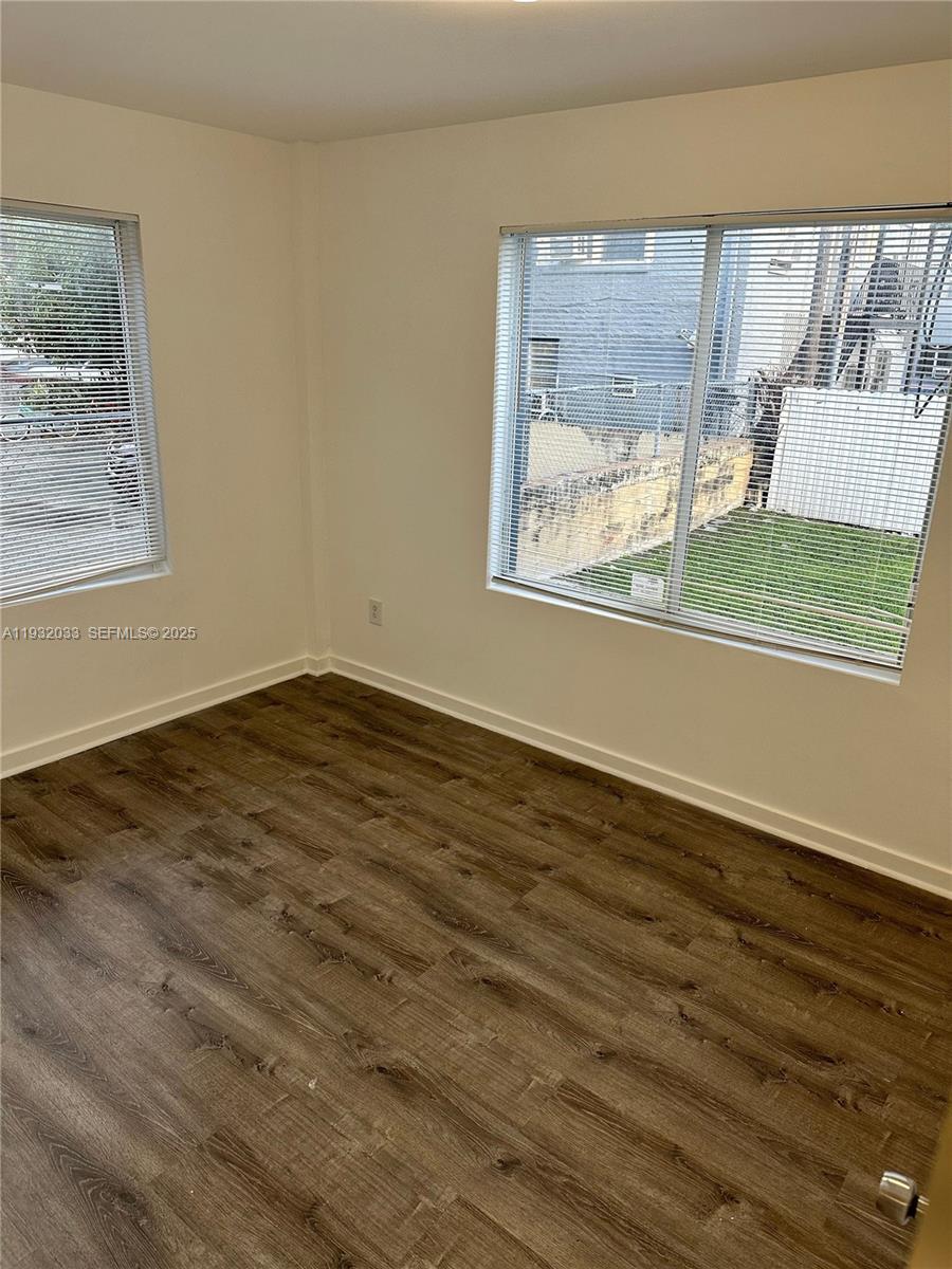 1129 Northwest 3rd Street, Unit 202 Miami, FL 33128 - Photo 9 of 10 a view of an empty room with wooden floor and a window