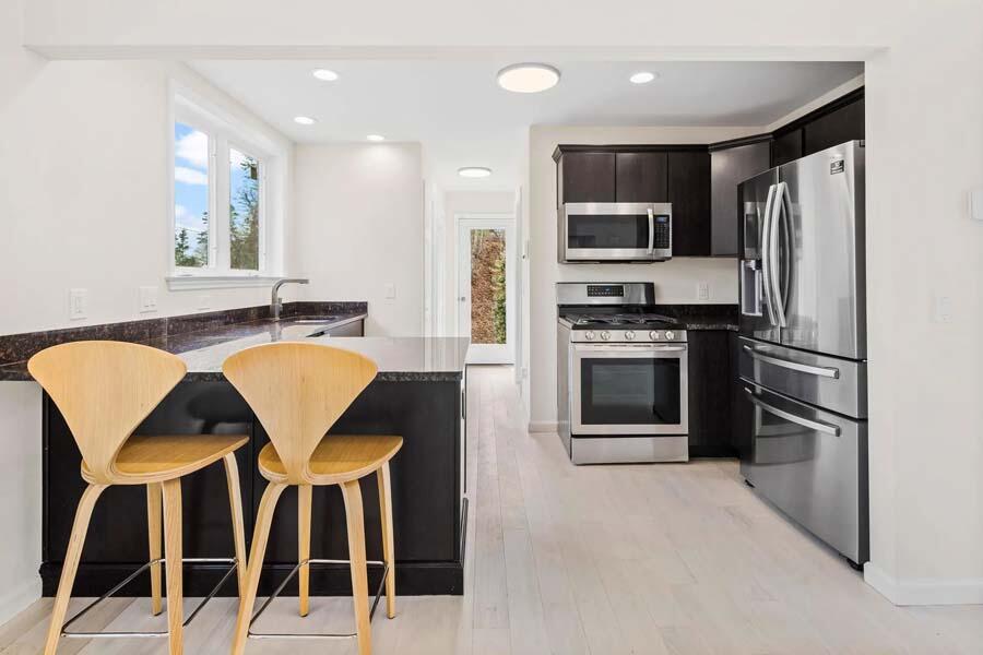 135 Old Truro Road Wellfleet, MA 02667 - Photo 7 of 38 a kitchen with stainless steel appliances kitchen island granite countertop a refrigerator a stove a microwave oven a sink with island and chairs