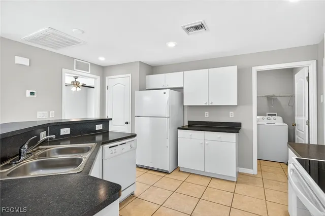 a kitchen that has a sink a stove a refrigerator and white cabinets