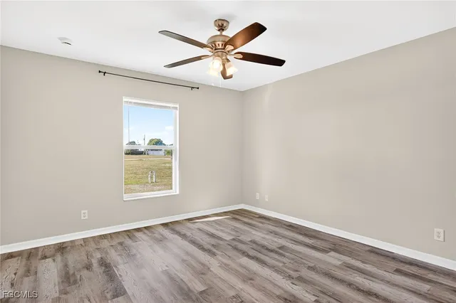 an empty room with wooden floor and ceiling fan