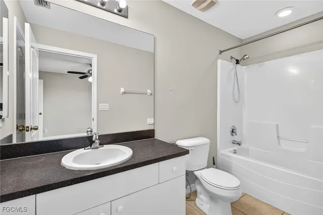 a bathroom with a granite countertop sink toilet a mirror and shower