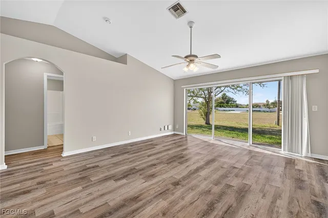 a view of an empty room with a window and wooden floor