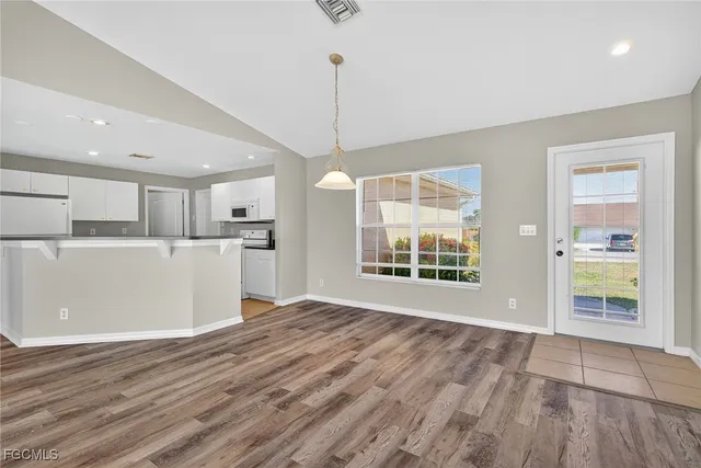 a view of an empty room with kitchen and a window