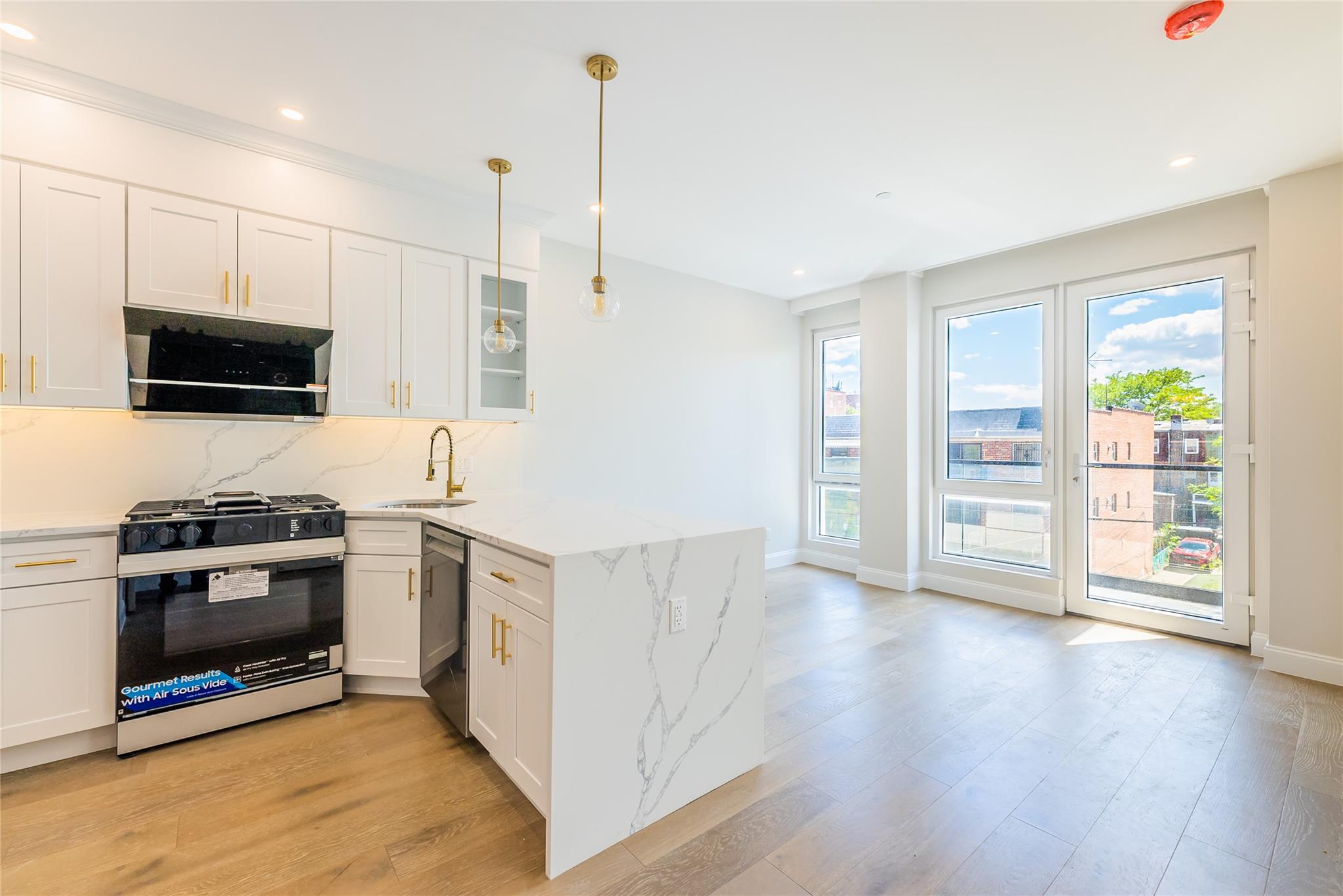 42-09 Hampton Street, Unit 4B Queens, NY 11373 - Photo 4 of 16 a kitchen with stainless steel appliances kitchen island granite countertop a stove a sink and a refrigerator