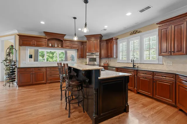 a kitchen with kitchen island granite countertop wooden floors and white cabinets