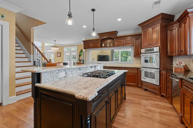 a kitchen with stainless steel appliances granite countertop a kitchen island a stove and a sink