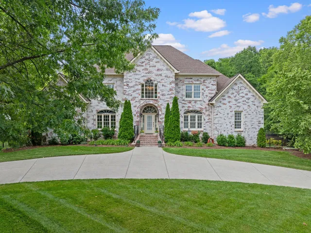 a view of a house with a yard and large tree