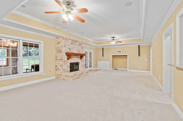 a view of a livingroom with a fireplace a ceiling fan and windows