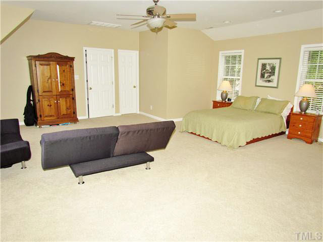 7316 Glendower Road Raleigh, NC 27613 - Photo 13 of 25 a bedroom with a large bed and a chandelier