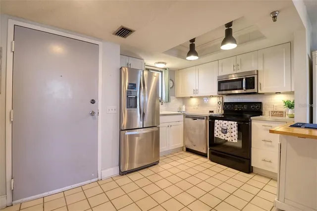 a kitchen with granite countertop a refrigerator and a stove top oven