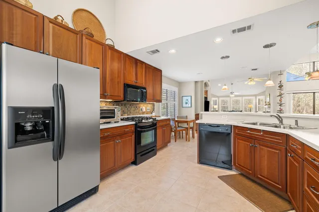 a kitchen with stainless steel appliances granite countertop a refrigerator a sink a stove and a refrigerator