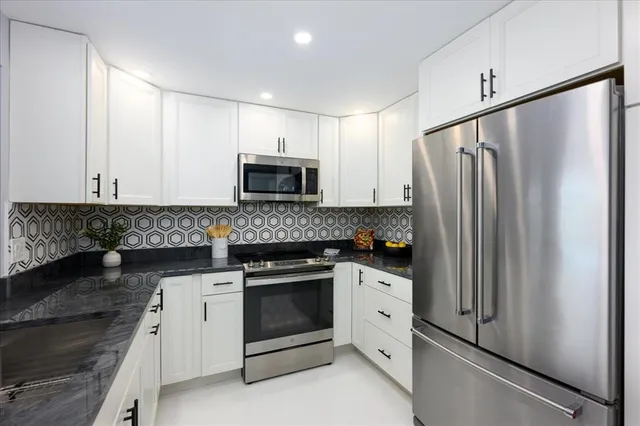 a kitchen with white cabinets and stainless steel appliances