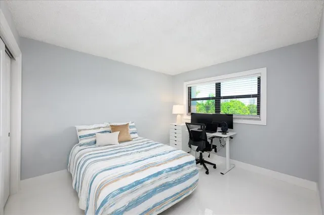 a bedroom with a bed and a desk next to a window