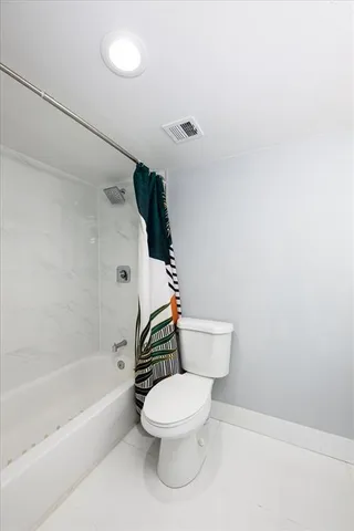 a white toilet sitting next to a bath tub