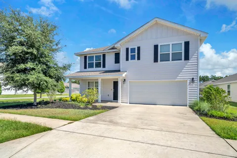 a front view of a house with a yard and potted plants