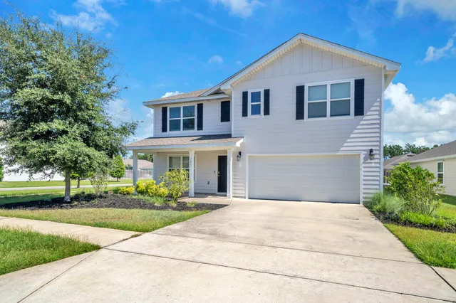 a front view of a house with a yard and potted plants