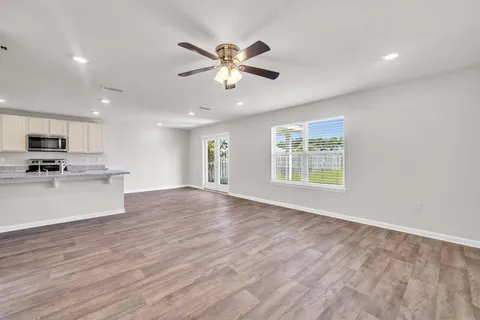 a view of an empty room with window and wooden floor