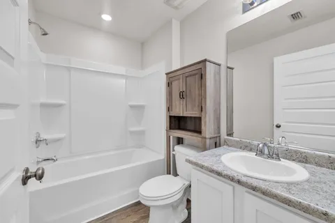 a bathroom with a granite countertop sink a toilet and a bathtub