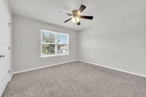 an empty room with ceiling fan and windows